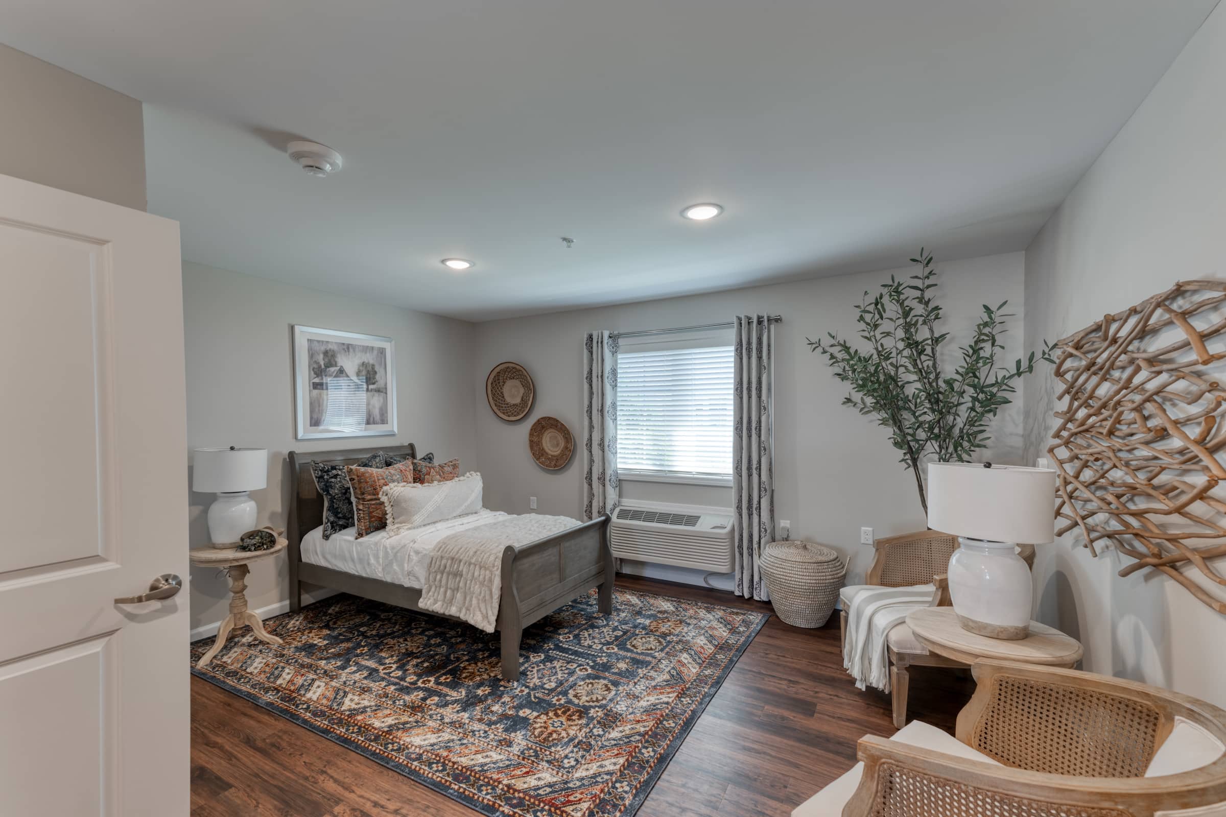 Cedarhurst Farmington bedroom featuring a comfortable bed and area rug over hardwood floors